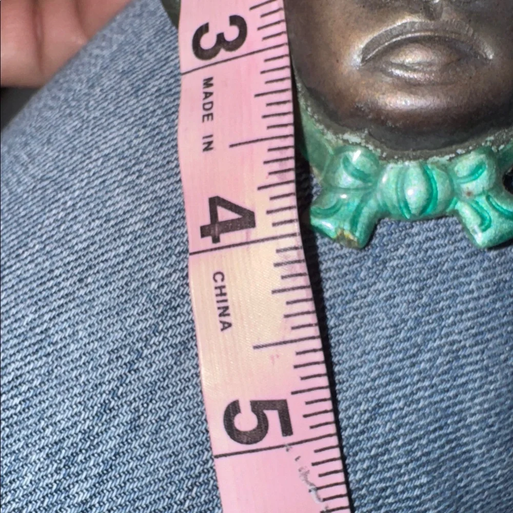 Vintage enameled metal decorative mask of an Asian man's face.